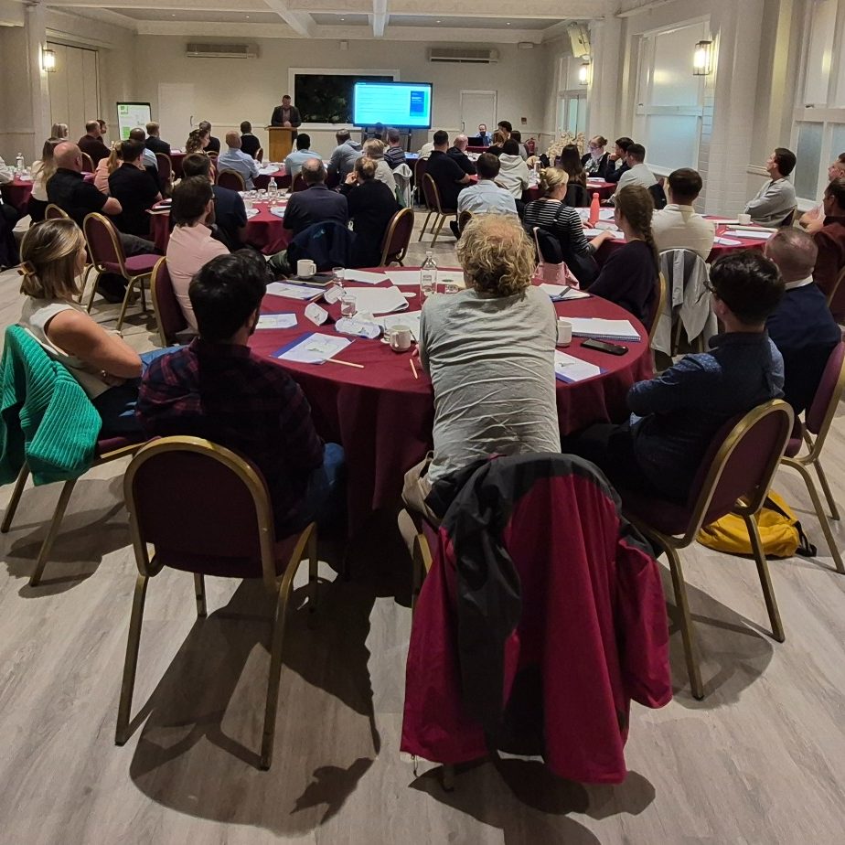 A speaker at a podium presenting to a room full of people